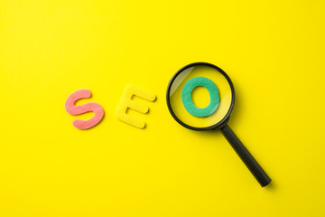 SEO Search Engine Optimization multi color logo alphabets ranking concept with magnifying glass on yellow background, SEO is one of online marketing business strategy to promote website.