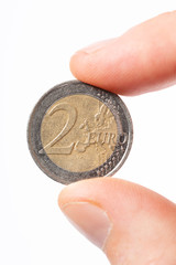 Close-up of caucasian male fingers holding a two Euro coin €2 on a white background.