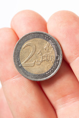 Close-up topview of a two Euro coin on caucasian male fingers on a white background.