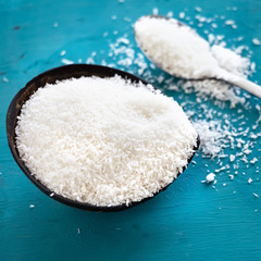 Coconut powder in coconut shell cup blue wooden background. Square image.