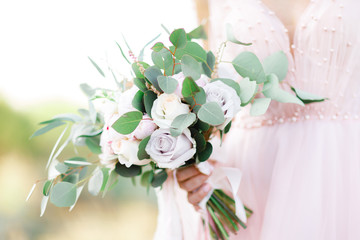 Fototapeta na wymiar bride's hands hold beautiful bridal bouquet outdoor