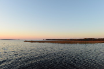 Blue sky with bright colors of sunset afterglow on a forest lake on an autumn evening