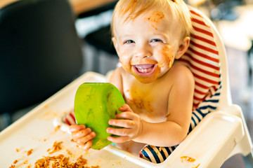 Little baby eating spaghetti dinner and making a mess