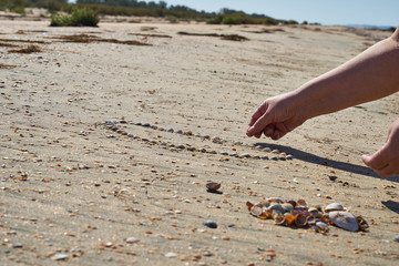 Girl lays out a drawing in the sand.