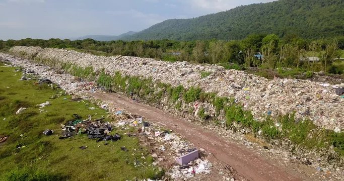 Long take bird's eye view of garbage mountain from drone in the industrial zone. See the employee take garbage to sell to earn extra income. Here is a flock of white birds, living in the garbage dump.