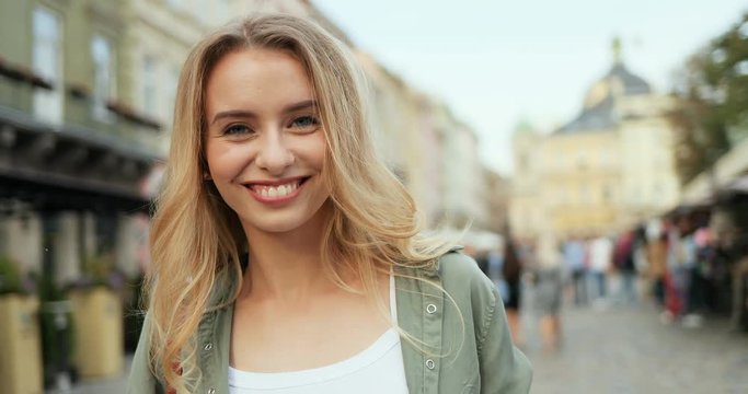 Pretty Caucasian blond girl taking a photo in front of the camera and smiling as being a tourism blogger. Close up. Portrait.