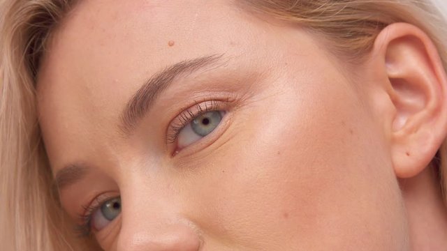 closeup of green eyes of nordic model with blonde hair. Ideal skin, strobbing shiny skin, millennial model, studio, blowing hair