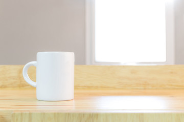 White coffee mug on wooden background in morning environment. Blank drink cup on product shelf for montage you design.