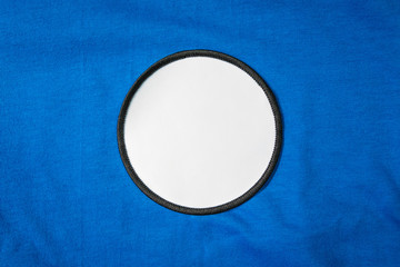 Blank arm patch on blue sport shirt. White team logo and emblem for your montage or edit.