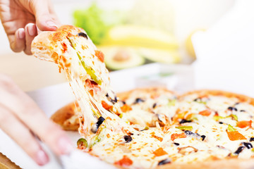 Slice of hot pizza with pepperoni and olives and mozzarella cheese drips