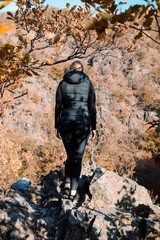 Back view portrait of a girl overlooking a mountain valley with orange autumn color tones. Bode Gorge (Bodetal), National Park Harz Mountains, Thale,  Saxony-Anhalt in Germany