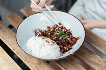 Close up of chinese food. Tso's chicken with rice in white plate on the table.