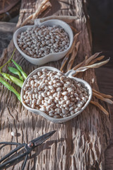 Dry grains of white beans lie on a wooden table in a white plate. Vegan food, animal protein substitute