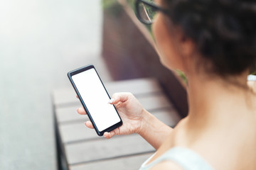 Young woman holding mobile phone with blank empty screen and texting message.