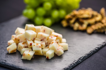 Cheese pieces juicy grapes and walnuts on slate board