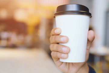 young man hand holding Paper cup of take away drinking coffee hot on cafe coffee shop.	