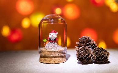 Santa Claus on cube ice in glass tube near pine cone isolated from Christmas light background
