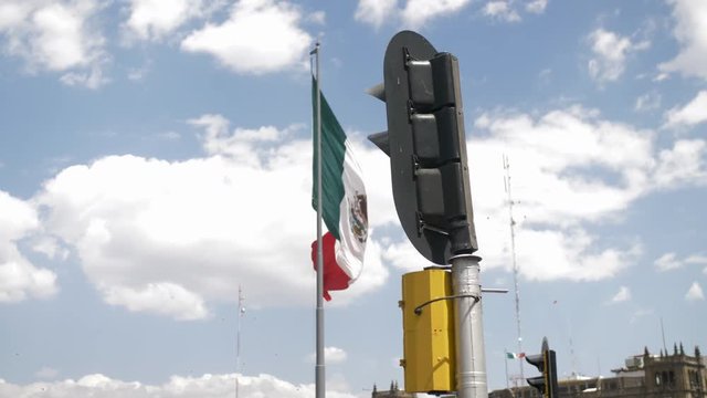 Mexico's National Flag in Mexico City Being Revealed From Behind Street Light in Front of Blue Cloudy Sky During Sunny Day. Shot in Slow Motion for Dreamy Effect.