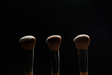 Professional makeup brush with powder on a black background