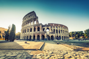 Fototapeta premium Koloseum w Rzymie, Włochy, o wschodzie słońca. Kolorowe tło podróży.