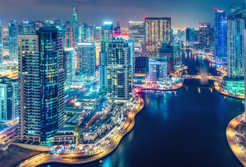 Obraz premium Malownicza nocna panorama dużego nowoczesnego miasta z oświetlonymi wieżowcami. Widok z lotu ptaka Dubai Marina, Zjednoczone Emiraty Arabskie. Wielobarwny tło podróży.