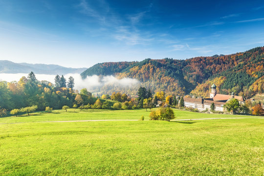 Scenic foggy mountain landscape with old monastery in Black Forest, Germany. Colorful travel background.