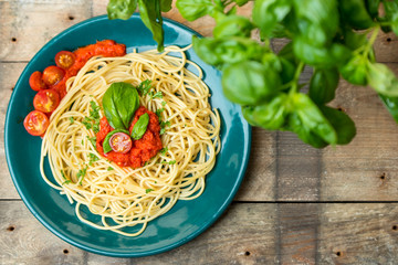 pasta with herbs, basil and tomato sauce served on green pate in rustic kitchen