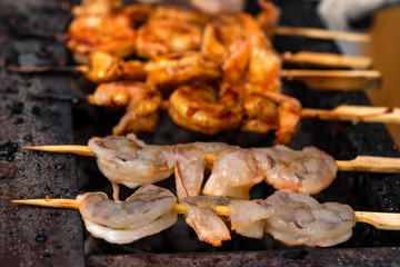 Grilled fried seafood on skewers on metal grid