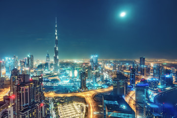 Fototapeta na wymiar Aerial view on big futuristic city by night. Skyscrapers of Dubai, United Arab Emirates. Nighttime skyline.