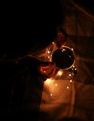 Home atmosphere. Cosiness. Warm colors. A mug of tea in the hands of the girl is enlightened with...