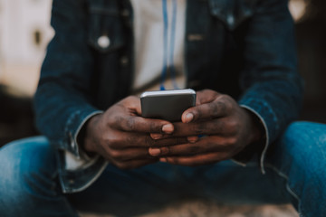 Modern user. Close up of a smartphone being used by a yougn afro american man