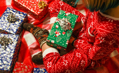 The girl is sitting and hugging New Year's gifts. Christmas boxes. Gift card. Black, blue and green packaging.