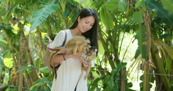 Woman feed Squirrel Monkey in zoo park