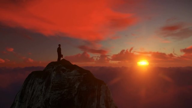 Isolated Businessman on top of a mountain above clouds, against beautiful sunset, drone flight 4K