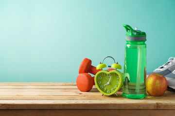 Fitness background with bottle of water, dumbbells and alarm clock