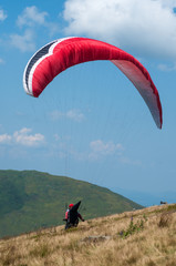 Paraglider flies over a mountain valley on a sunny summer day. Paragliding in the Carpathians in the summer.	