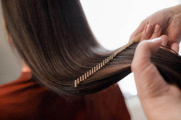 Close up of hairdresser making hair styling for woman while combing by hairbrush