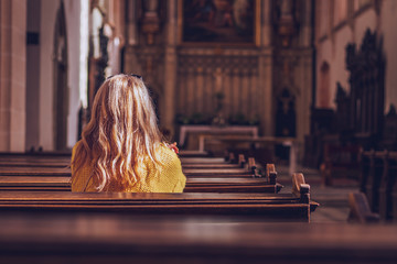 Young woman praying and meditating in church.  - obrazy, fototapety, plakaty
