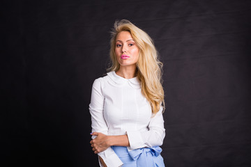 Fashion and people concept - young blonde woman standing over the black background with copy space