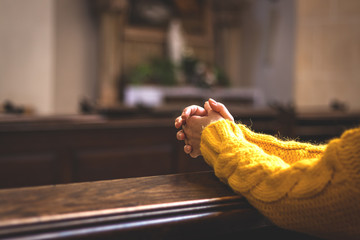 Christian woman is praying with hands crossed in church
