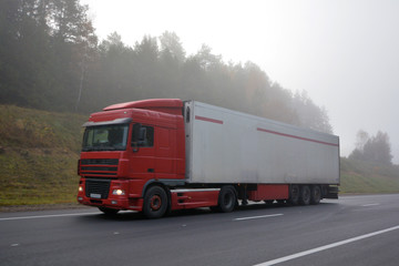 Truck is driving along the road in the morning in a thick fog