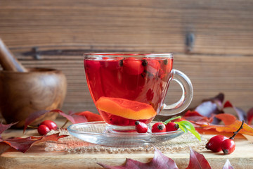 A cup of rosehip tea with fresh rosehips