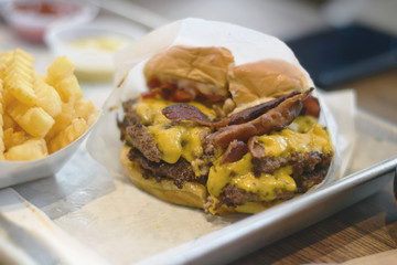 Delicious juicy bacon cheeseburger with fries on restaurant tray