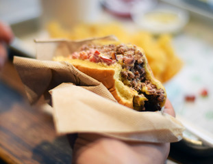 Hand holding hamburger in napkin at a restaurant