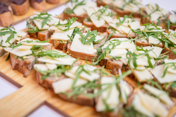 Catering / Belegte Brote mit Käse und Ruccola auf Holzbrett