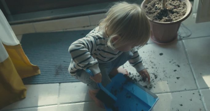 Little toddler using brush and dustpan