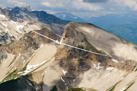 Segelflugzeug fliegt kreisend über Bergen