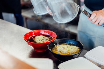 Chef boiling ramen noodle in soup for making miso and shoyu ramen.