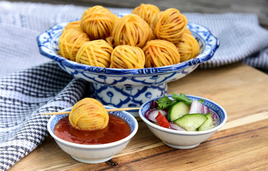 Deep Fried Wrapped Pork with Noodle Thai traditional snacks menu ( Thai name is Moo sarong) in Thai style bowl with cucumber salad and sweet chili sauce.