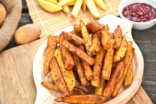Homemade Crispy Seasoned French Fries..French fries  with spicy seasoning in wooden plate on wooden broad.